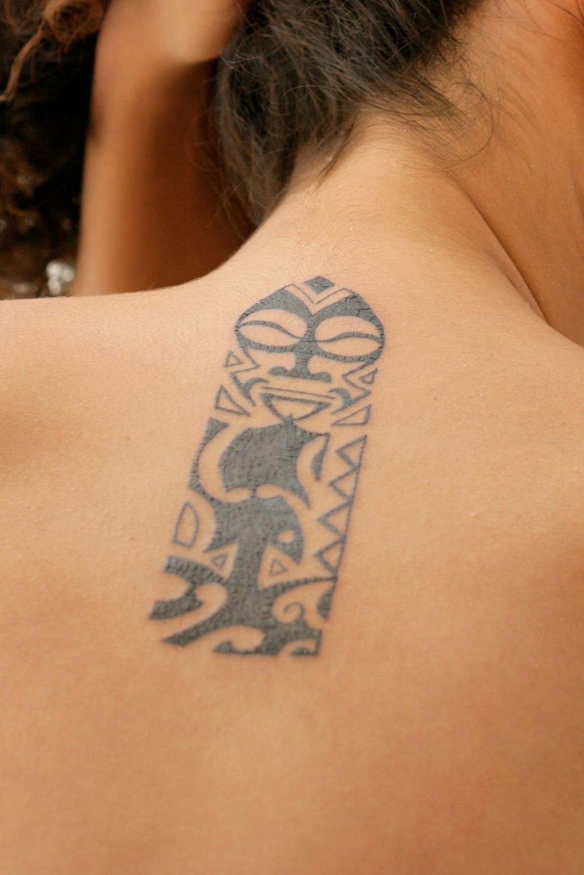 Tatouage noir avec motifs tribaux visible sur la nuque d’une personne dans l’univers du tatouage  à Delson