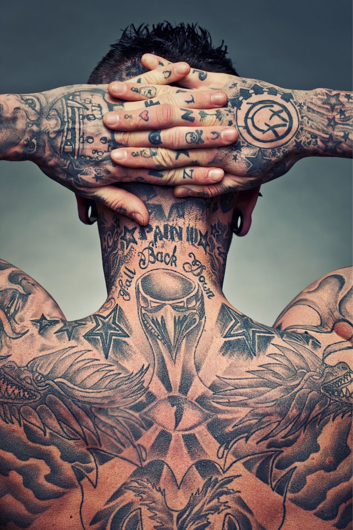 Personne avec de nombreux tatouages visibles sur le cou, les bras et les mains dans l’univers du tatouage  à Prévost